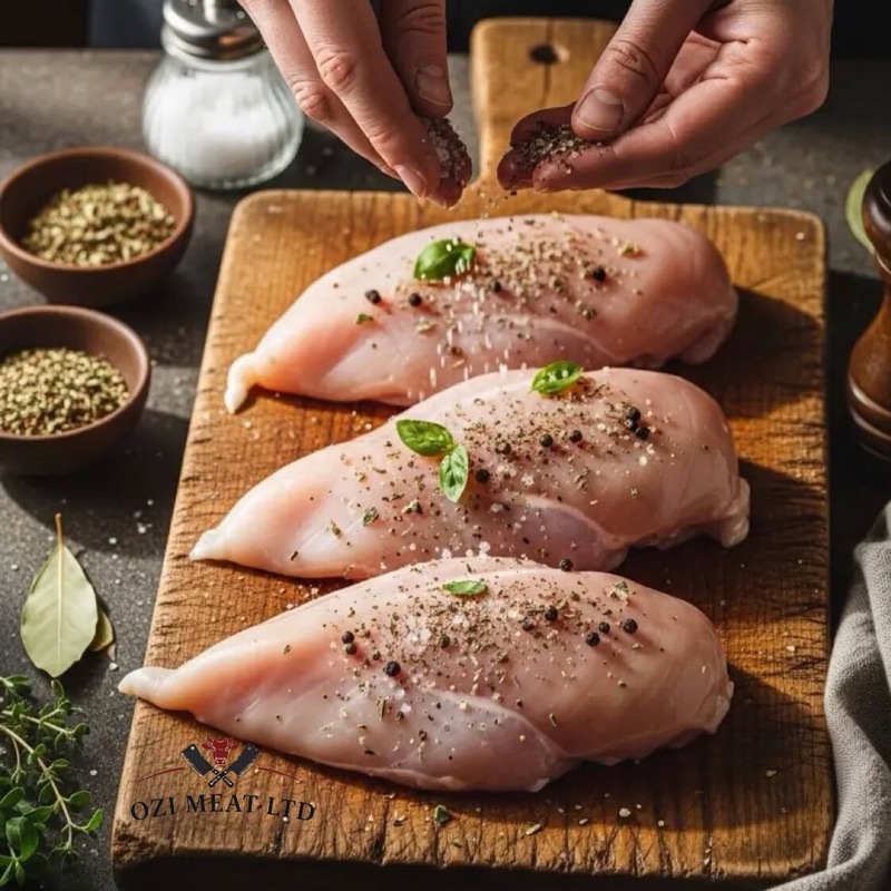 Chicken breast fillets being seasoned on a board